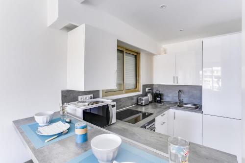 カンヌにあるIMMOGROOM - Renovated apartment - Terrace - AC - Wifiのキッチン(白いキャビネット、カウンタートップ付)