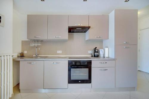 une cuisine avec des armoires blanches et un four noir dans l'établissement IMMOGROOM - Terrace - 2 bedrooms - Downtown - Air conditioning - Wifi, à Cannes
