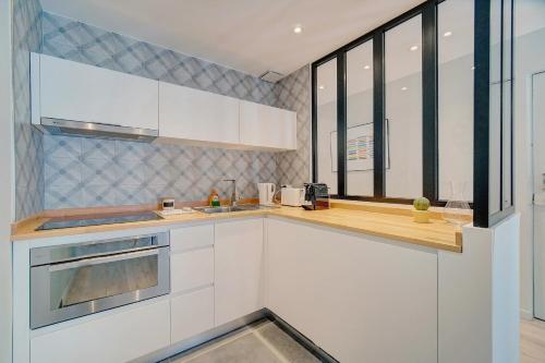 une cuisine avec des placards blancs et une grande fenêtre dans l'établissement IMMOGROOM - AC - 5min from the beaches 8 min from Palais, à Cannes