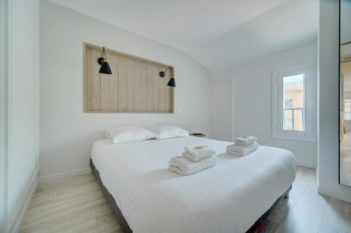 une chambre blanche avec deux lits avec des serviettes dessus dans l'établissement IMMOGROOM - AC - 5min from the beaches 8 min from Palais, à Cannes