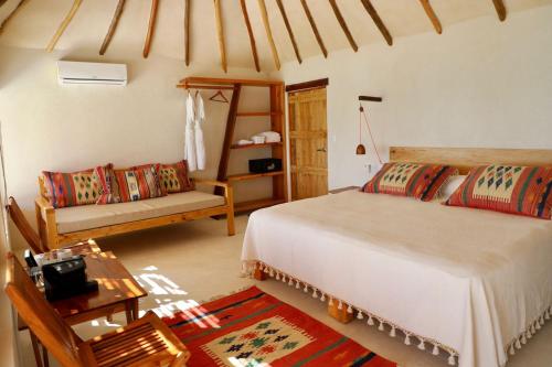 a bedroom with a bed, chair, table and lamps at Hotel Poc Na Tulum in Tulum