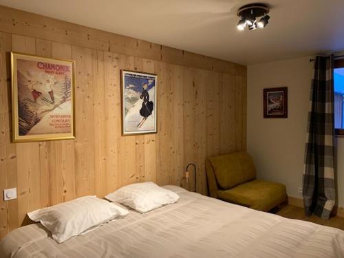 een slaapkamer met een bed, een stoel en posters bij CHALET Mitoyen LE RUSTICANA in Chamonix-Mont-Blanc