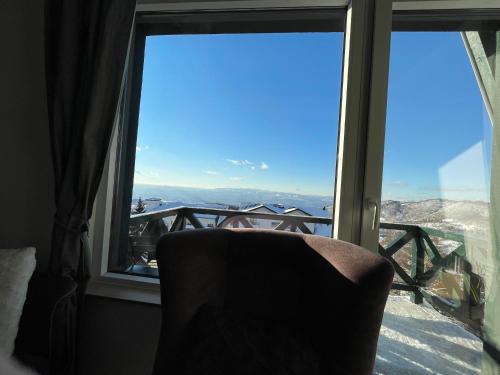 a chair sitting in front of a window with a view at Pano Kopaonik Panorama in Kopaonik
