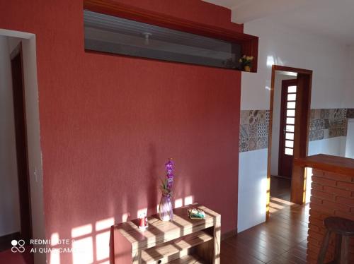 a living room with a red wall and a table at Cantinho Feliz a 900m do Capivari in Campos do Jordão