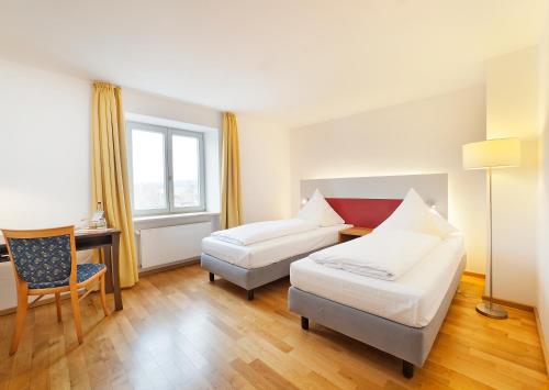 a hotel room with two beds and a desk at AKZENT Brauerei Hotel Hirsch in Ottobeuren