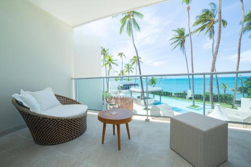 a balcony with a chair and a table and palm trees at Presidential Suites Cabarete - Room Only in Cabarete