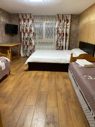 sypialnia z 2 łóżkami i telewizorem oraz drewnianą podłogą w obiekcie Котедж Два Леви w Sławsku