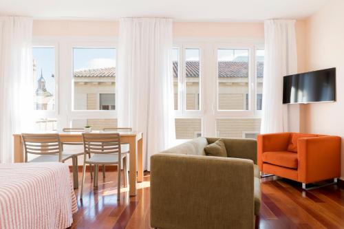 a living room with a couch and a table and chairs at Apartamentos Sabinas El Pilar in Zaragoza