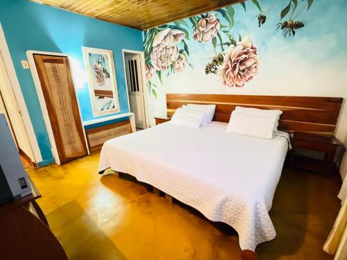 um quarto com uma cama branca com flores na parede em Hostal Colina de Lluvia em Filandia
