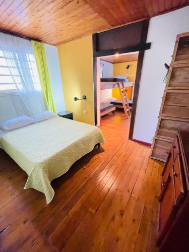 a bedroom with a bed and a wooden floor at Hostal Colina de Lluvia in Filandia