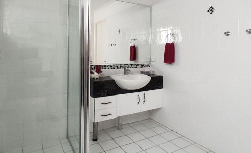 a white bathroom with a sink and a shower at Motel Myall in Dalby