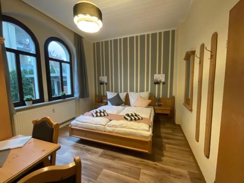 um quarto com uma cama, uma mesa e janelas em Pension Lindenhof em Dresden