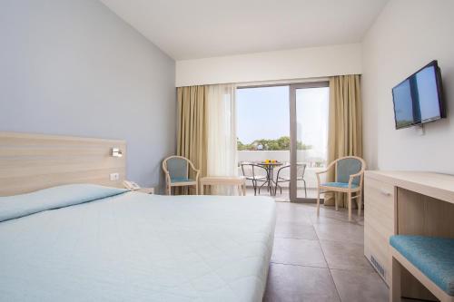 ein Hotelzimmer mit einem Bett und einem TV in der Unterkunft Hotel Niriides Beach in Kolymbia