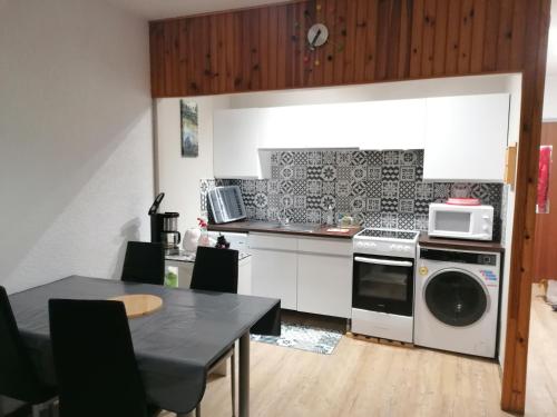 une cuisine avec une cuisinière et un micro-ondes dans l'établissement Studio 4 personnes, à Saint-Lary-Soulan