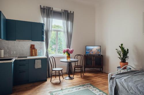 a bedroom with a table and a bed and a kitchen at Olive Apartment in Liepāja