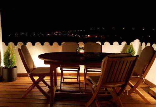 a wooden table and chairs on a balcony at night at Casa rural La Rabá Terraza con increíbles vistas in Sanlúcar de Guadiana