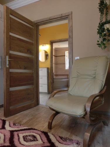a living room with a chair and a sliding door at Pilis Apartman in Piliscsaba
