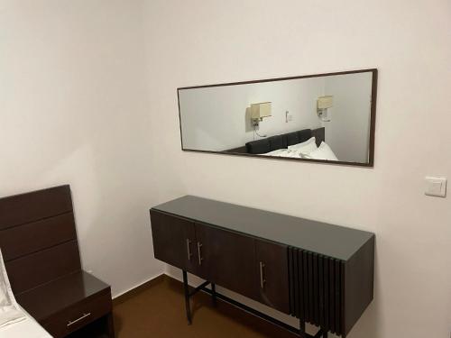 a mirror on a wall above a dresser in a bedroom at HOTEL LES ARCADES in Abomey-Calavi