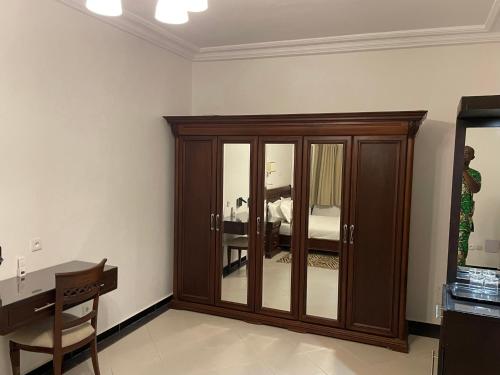 a room with a wooden cabinet and a bed at HOTEL LES ARCADES in Abomey-Calavi
