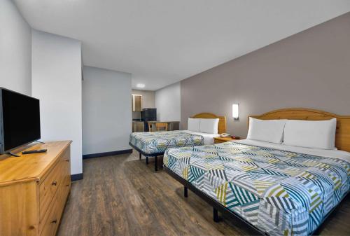 a hotel room with two beds and a flat screen tv at Studio 6-North Richland Hills, TX - Fort Worth in North Richland Hills