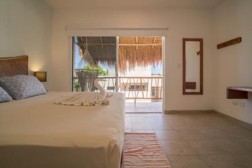 um quarto com uma cama e vista para uma varanda em Hotel Sonno Caliza Tulum em Tulum