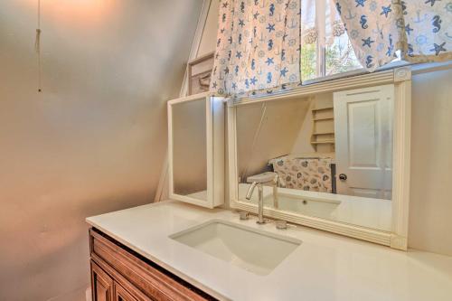 a bathroom with a sink and a mirror at Steps to Lake! Charming Cabin Pool Access and Decks in Granbury