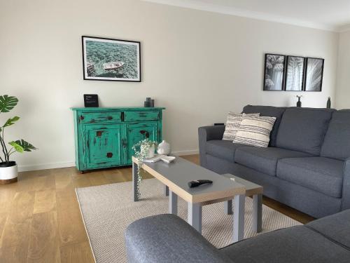 a living room with a blue couch and a table at Kiama Palms on Terralong in Kiama