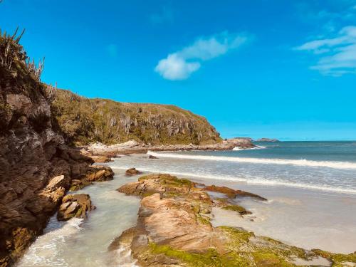 a beach with some rocks and the ocean at Pousada Areias do Pero in Cabo Frio