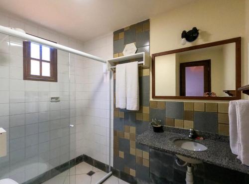 a bathroom with a sink and a shower with a mirror at Pousada Areias do Pero in Cabo Frio