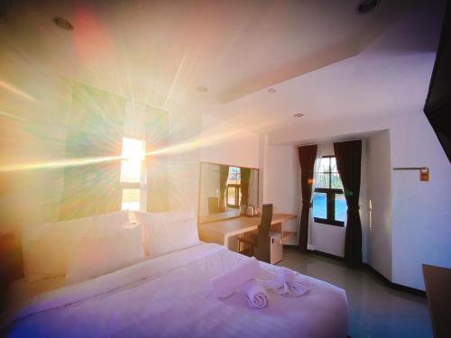 a bedroom with a large white bed and a window at Maze Pool Villa Resort in Kamphaeng Phet