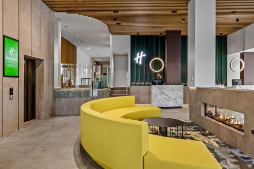 a lobby with a yellow couch and a fireplace at Holiday Inn Queenstown Remarkables Park in Queenstown