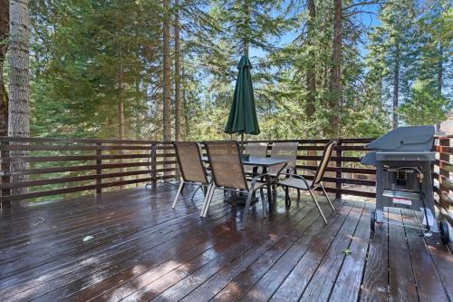 a deck with a table and an umbrella and a grill at Chief Peak in Fish Camp