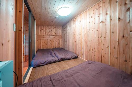 a bedroom with a bed in a wooden wall at Fukoji in Kawaba