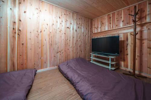 a bedroom with wood paneled walls and a flat screen tv at Fukoji in Kawaba