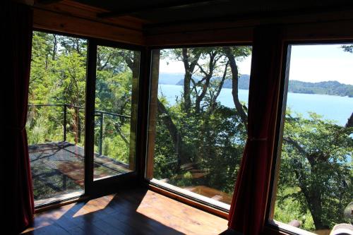 a room with windows looking out at the water at La casa providencia - Costa del lago in Villa Pehuenia
