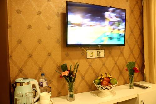 a television hanging on a wall with a table with fruit at Hotel Family Ties Pvt. Ltd. in Kathmandu