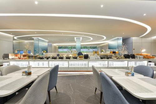a dining room with tables and chairs and a kitchen at Centre Point Prime Hotel Pattaya in Pattaya North