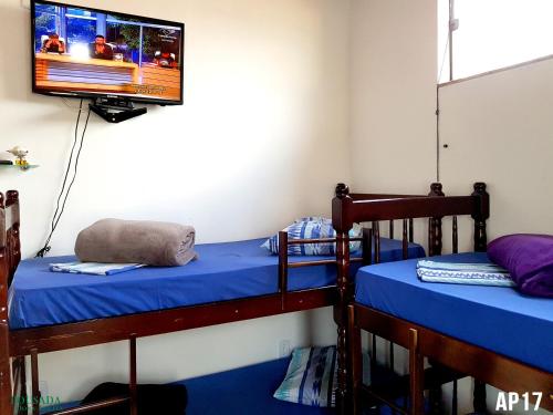 two bunk beds in a room with a tv on the wall at Pousada Dona Lolita in Cachoeira Paulista