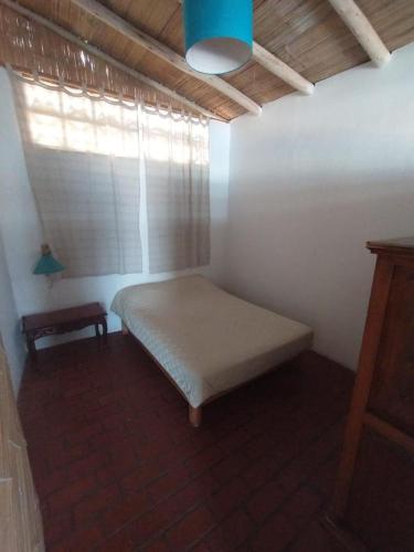 a small bedroom with a bed and a window at Hamacas in Punta Negra