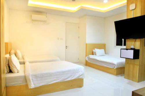 a bedroom with two beds and a flat screen tv at Arawa Traveller's Inn Motel in Makassar