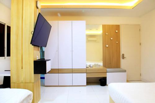 a bedroom with a tv and a white cabinet at Arawa Traveller's Inn Motel in Makassar