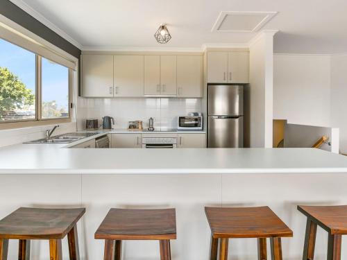 a kitchen with a large white counter and wooden stools at Bass River Farm in Bass