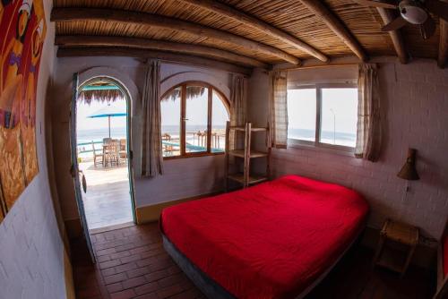 1 dormitorio con cama roja y vistas al océano en Hamacas, en Punta Negra