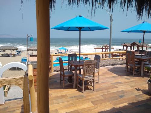 a patio with tables and umbrellas on the beach at Hamacas in Punta Negra