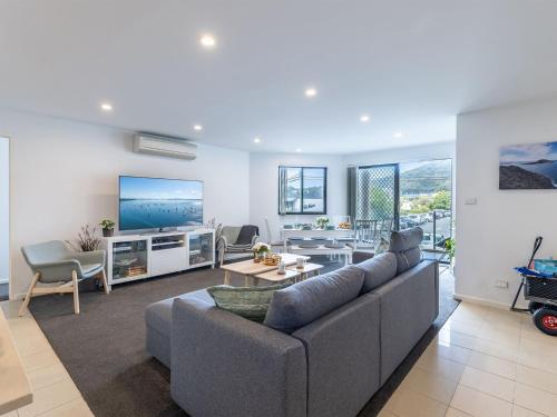a living room with a couch and a tv at Dolphin Cove 8, 2-6 Government Rd - Air conditioning, Wi-Fi, lift, secure parking and close to town in Nelson Bay