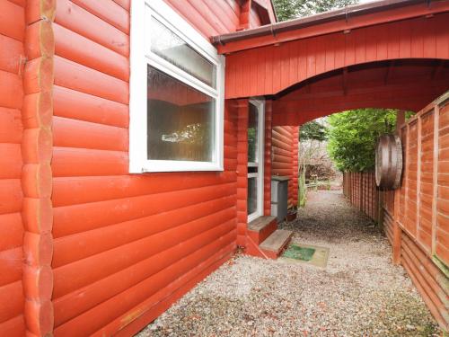 a red house with a window on the side of it at Rowan Lodge in Strathpeffer
