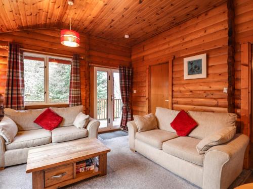 a living room with two couches in a log cabin at Rowan Lodge in Strathpeffer