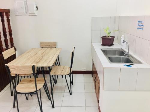 cocina con fregadero, mesa de madera y sillas en JPrime Apartelle en Tuguegarao