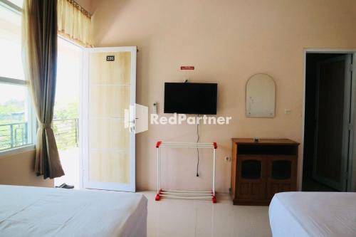 a bedroom with two beds and a tv and a window at Wisma Suci Syariah Polewali Mandar Mitra RedDoorz in Matakali