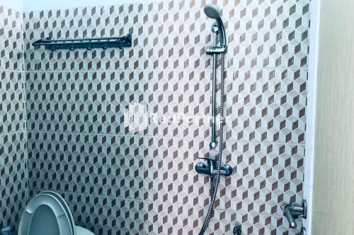 a shower in a bathroom with a tiled wall at Wisma Suci Syariah Polewali Mandar Mitra RedDoorz in Matakali